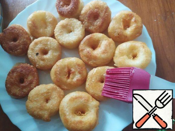 Ready-made doughnuts immediately transfer the skimmer to a previously prepared plate, cool, brush well impregnate the doughnuts with syrup.