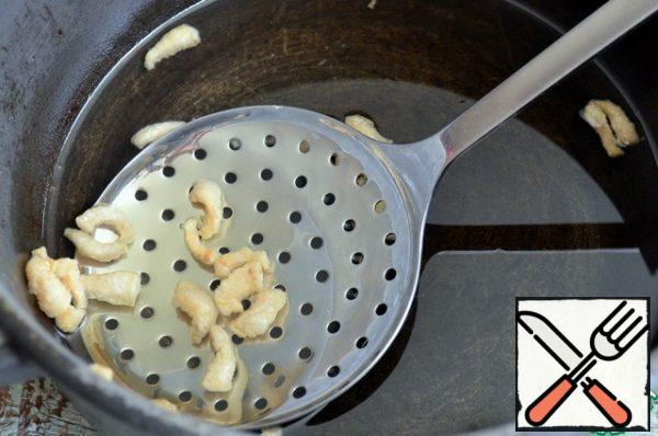 In 4 liters auldron, heat vegetable oil, fry pieces of fat in it. Then lay out the pork rinds.