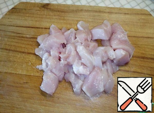 Cut the chicken fillet into small pieces. Transfer to a saucepan, cover with water and put on fire. Cook for 15 minutes over medium heat.