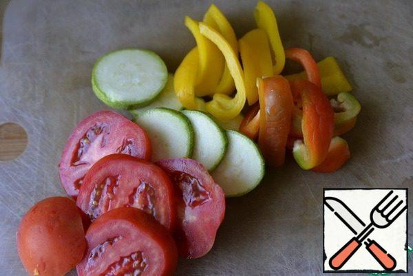 Wash vegetables, clean. The more varied the color of the vegetables, the brighter and more beautiful the appetizer. Peppers cut into strips, zucchini and tomato circles. Tomatoes take ripe, but dense, otherwise they will spread out.