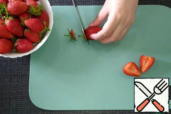 Wash the strawberries, dry them, and cut off the sepals. Part of berries cut in half, part of leave whole.