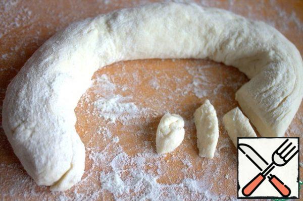 From half of the dough, we twist the sausage, divide it into pieces with a knife.