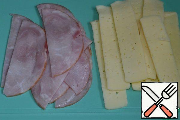 Cut the cheese and ham into thin strips corresponding to the width of the zucchini slices.