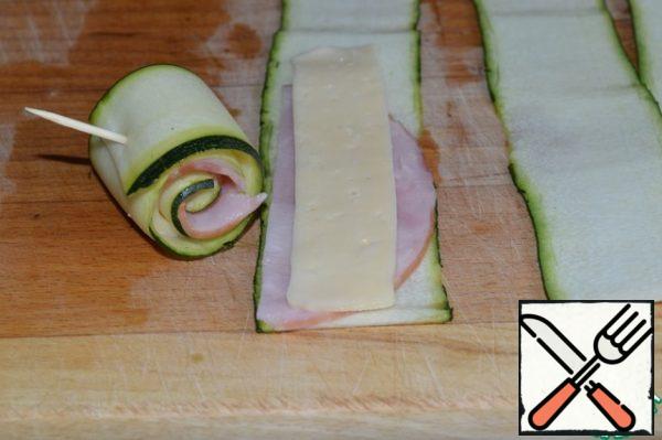 Put a strip of meat and cheese on each slice of zucchini.
