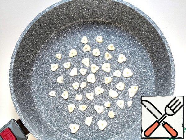 Peel the garlic and cut it into thin plates, put it in a dry pan, and brown it.