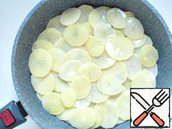 Mix garlic and onion, spread evenly on the bottom of the pan, put thin rings of potatoes on top, pour 3 tablespoons of vegetable oil, cover with a lid, simmer over medium heat for 7-10 minutes.