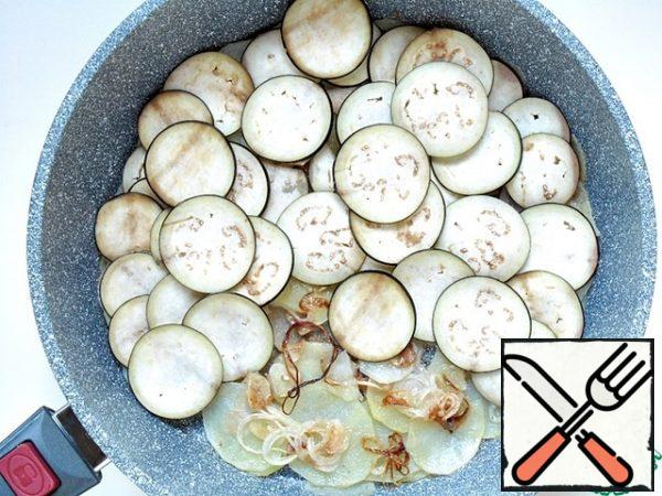 Carefully turn the potatoes and onions over with a spatula, spread the eggplant rings over the entire surface of the potatoes.
It is better to PEEL eggplants!