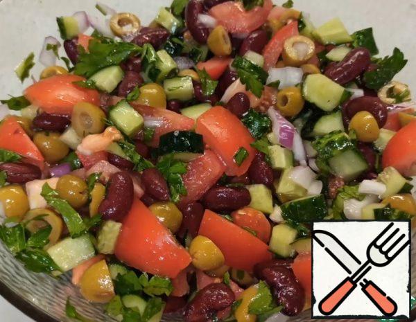 1. Cut the vegetables: cucumbers in cubes, tomatoes in medium slices, onions and herbs are crushed. Mix all the vegetables, add the canned beans (Canned beans must first be thrown into a colander to drain the liquid, and wash) and olives.
2. Salt, add oil and mix everything well.