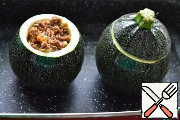 Grease barrels of zucchini with sunflower oil inside and out.
Fill with filling.  Cover with the top.
Place on a deep baking sheet.
Add a glass of water and bake in a preheated oven at 180 g for 35-40 minutes.