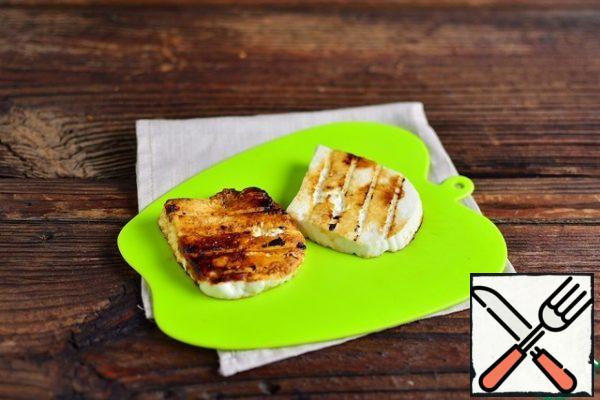 Fry two slices of cheese on the coals inside the grill, turning once until toasted, as it cools, remove from the grill.