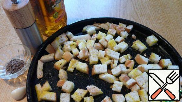 To begin with, we will prepare homemade crackers. Three or four slices of white loaf cut into small pieces. Salt, pepper, sprinkle a little cumin seeds, squeeze a clove of garlic and sprinkle with mustard oil. Mix and put in the oven to dry until Golden.