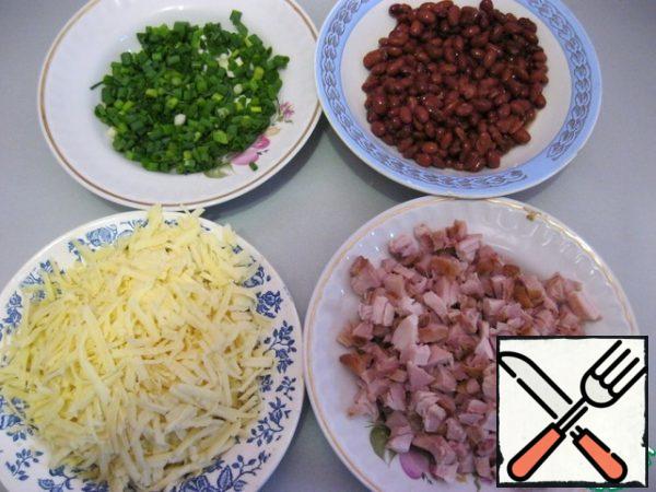 Finely chop the washed and dried green onions. Grate the cheese on a large grater. Separate the smoked chicken fillet from the bones and cut into small cubes. Open the beans and pour out the excess liquid.