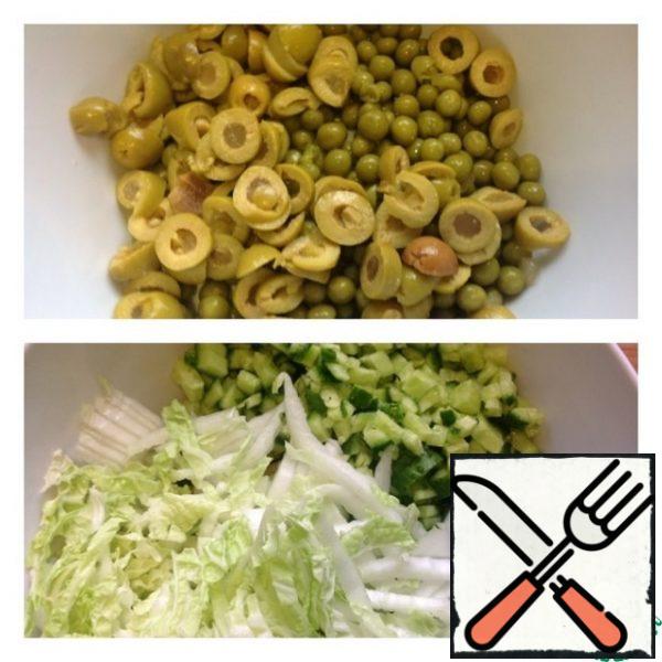 Drain the liquid from the peas and put 5 tbsp of Olives in a salad bowl. Cut the cucumber into small cubes and chop the cabbage.