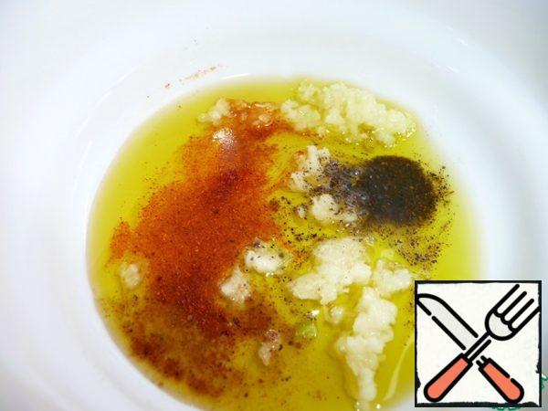 Preparing the salad dressing.  Squeeze the garlic into the olive oil, add the mixture of peppers, salt, sugar, ginger, nutmeg.