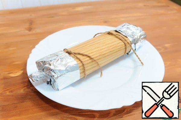4. Wrap a sheet over the food, overlapping the edges at the top, and tie the roll with damp twine.  Foil the ends so that the melted cheese does not flow out of the roll.