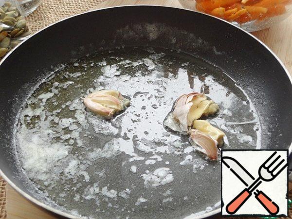Melt both oils in a frying pan, add the crushed garlic, leave the husks on, and flavor the oil for a couple of minutes.