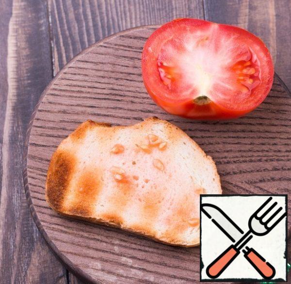 RUB the bread with garlic, once again brush well with butter and soy sauce, and then lightly soak.
Cut the tomato into halves and RUB the bread well with the tomato.