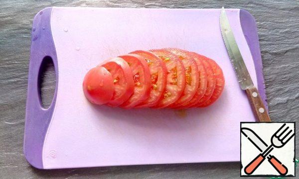 Cut the tomato into slices and place on a plate.