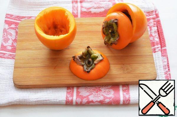 Cut off the tops of persimmons and remove the pulp, leaving the walls 0.5-0.6 cm.
Persimmon pulp is not needed in the recipe, it can be used in other dishes or just have a snack while preparing an appetizer.