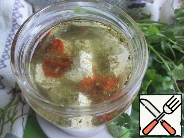 To make the cheese marinate faster, it is advisable to warm up the filling oil a little. Put it in a saucepan, add the lemon juice and a pinch of the remaining herbs. Put on fire and heat until warm, 1 - 2 minutes. This time I took vegetable oil.
Add the warm oil to the jar. At first, the marinade will be cloudy, but after a while it will become transparent.