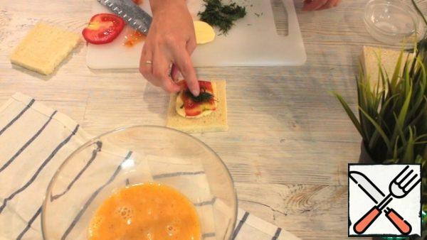 Next, we collect our sandwich. Put a piece of bread, then cheese, tomato, sprinkle with herbs on top and cover with a second piece of bread.
We do the same with the second sandwich.