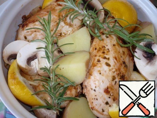 Take a baking dish, put the fried chicken fillet in it, add the chopped mushrooms and potatoes cut into quarters, pour the juice of the remaining lemon. Top with the rosemary sprigs and lemon halves that were squeezed out of the juice.