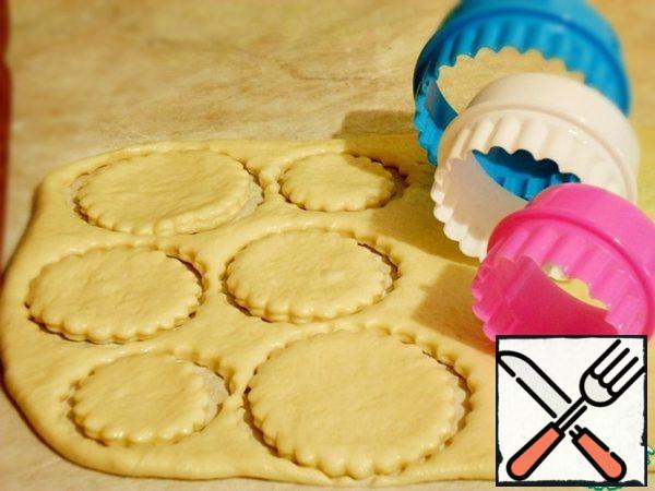 After 20 minutes, the rested dough can be cut.
Roll out in a layer 7-10 mm thick, cut out different-sized circles with pastry cuts, you can use cups of different diameters.