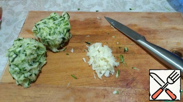 Zucchini three on a large grater. Salt, mix and leave for a few minutes. Then squeeze, pour the juice.
Finely chop the garlic.