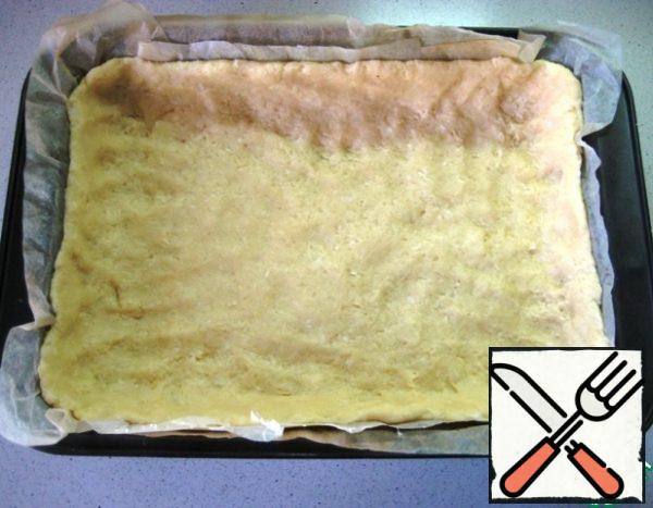 Cover the baking dish with parchment (the size of the form is 27 cm x 20 cm), spread the dough on the bottom of the form and form the sides.