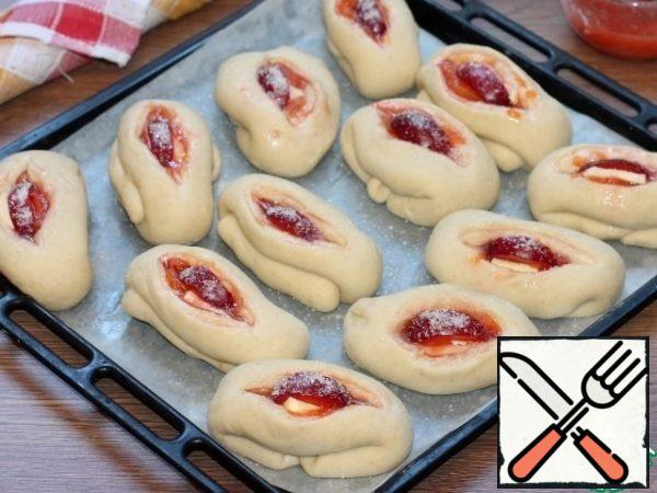 Use scissors to make a cut on the blanks (in the middle). Put a small cold piece of butter, cooked jam and slices of unpeeled plum in the cut. Sprinkle sugar on top. Send the baking sheet with the blanks to the preheated 180 C oven for 30-35 minutes.