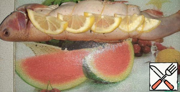 Cut the lemon. Tie the trout with a thread, put lemon slices on the sides under the thread.