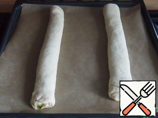 Roll along the length of the roll, the seam is well fastened and put on a baking sheet. covered with baking paper. Do the same with the second half of the dough. Leave a larger distance between the rolls so that there is space for weaving.