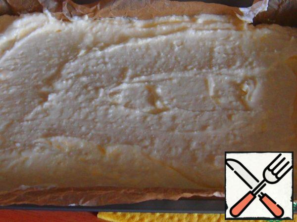 Cover the form with baking paper. Pour out half of the dough, flatten. Put the curd filling on top and smooth it out with a spoon dipped in water.