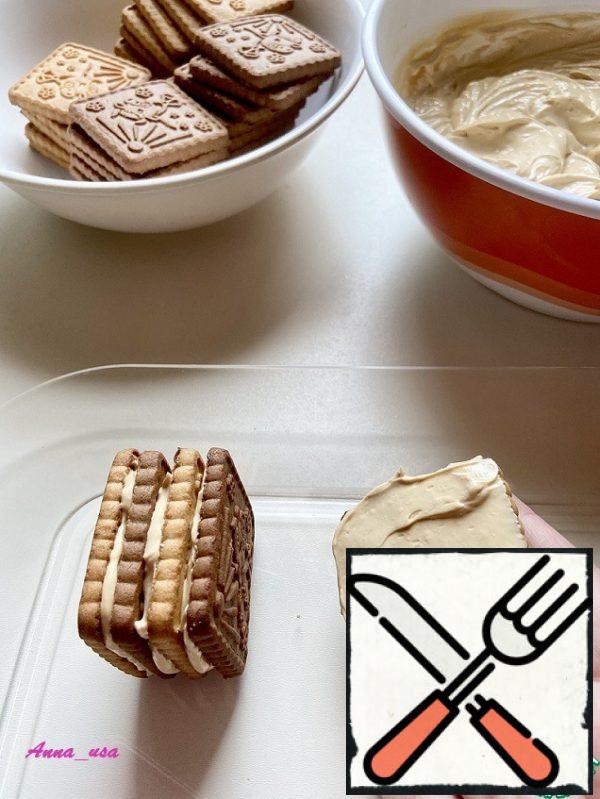 We put it on a dish, we put it and not put it. Due to this, the cut will be unusual. So alternating colors, spreading cream on each cookie, we attach them to each other.