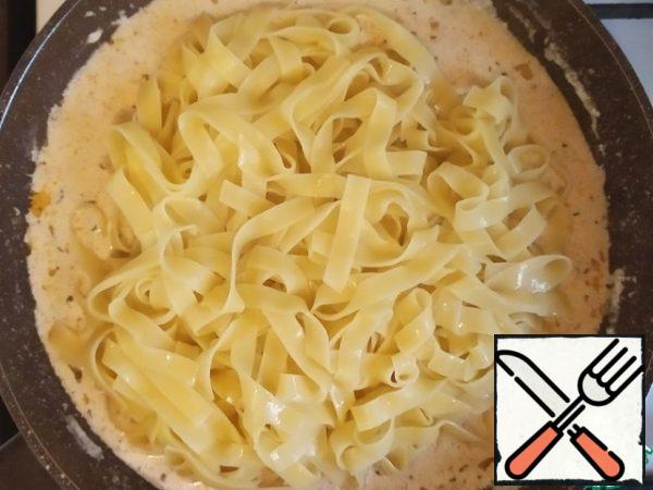 When the fettuccine is ready, pour a Cup of water from them and transfer to the sauce, then mix thoroughly.