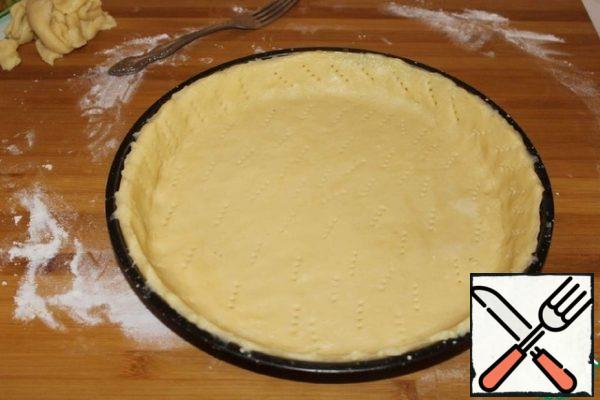 Roll out the dough into a layer. Spread in a form greased with butter. Transfer the dough to the mold. Remove excess dough around the edges. We make punctures with a fork.