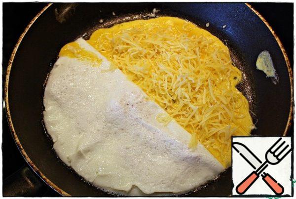After the protein is wrapped, pour half of the yolk on the empty part of the pan, wait for it to set and pour half of the cheese. Cover with half of the meat product.
