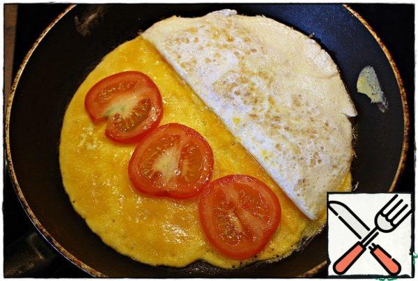 On the empty part of the pan, pour the second part of the yolk, after setting, spread the tomatoes and cover with half of the filling.