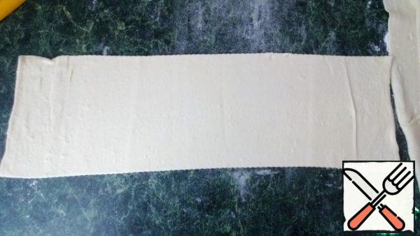 The finished puff pastry is slightly rolled out, cut into 4 strips 8-10 cm wide.