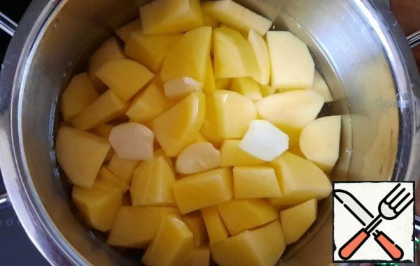 Peel the potatoes, cut into small cubes, peel the garlic, cut in half, and boil in salted water for 20 minutes.