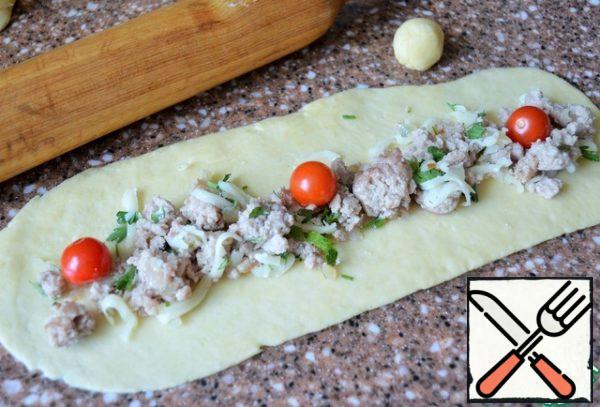 From each pinch off a small piece, 10-12 g. Roll out the most part in a long rectangle, the smaller in a circle. Weigh the minced meat and divide it into 10 parts.
Spread the minced meat in length, add the cherry.