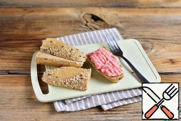 Take a piece of baguette, spread it with minced meat, like pate with a fork.