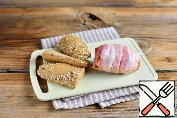 Put the cheese, tomato and onion on the minced meat. Wrap the sandwich in bacon.