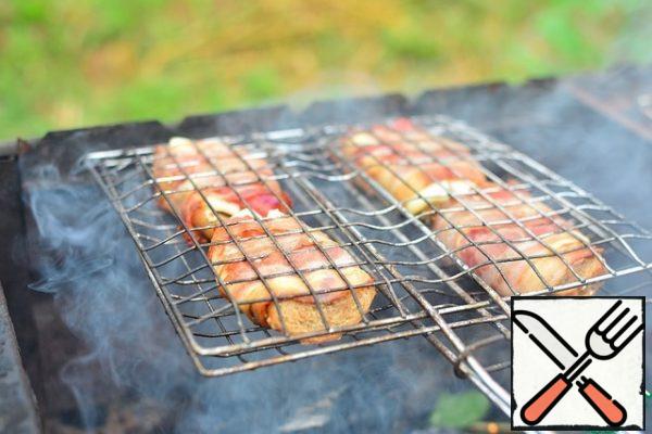Fry on a grill rack, over moderately hot coals, turning until the bacon crunches.