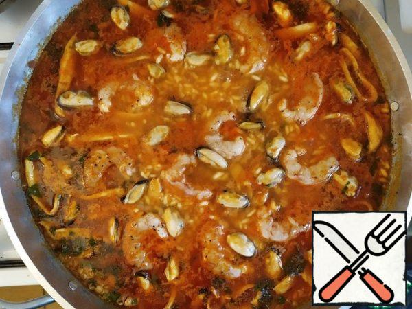 After 8 minutes, when the rice appears from under the broth, put the shrimp and mussels.
And after a couple of minutes, reduce the heat to low.