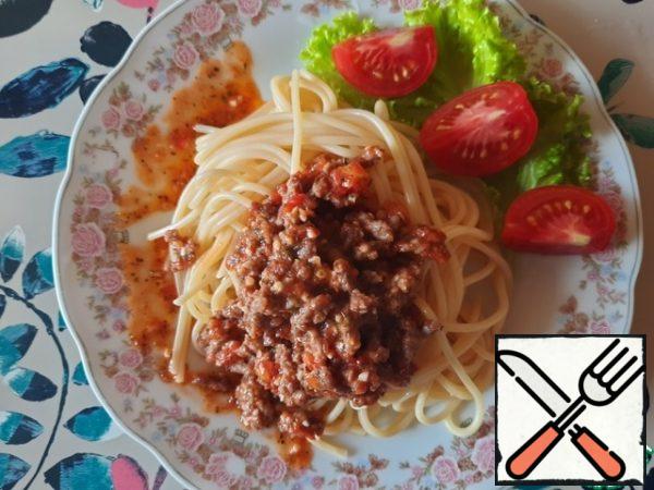 Place the spaghetti on a plate, add the Bolognese sauce, and garnish with grated cheese.