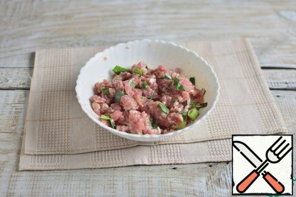 In the minced meat, add garlic through a press, chopped green onions, salt to taste, stir.