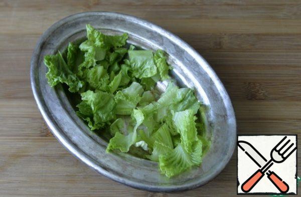 We take a salad bowl to serve on the table, put the washed, dried lettuce leaves into it.