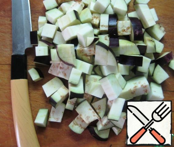 Cut the eggplant into small cubes. Put in a deep container, pour salted, cold water and leave for 30 minutes. Then drain the water, wash the eggplant and let the excess liquid drain.