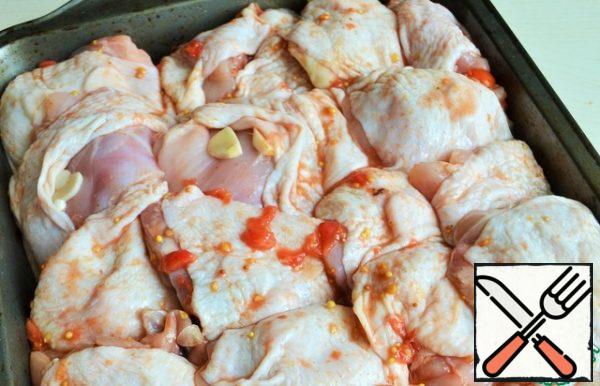 Peel the garlic and cut it into thin slices. Under the skin, spread 1-2 garlic petals. Transfer the thighs to a deep baking tray.